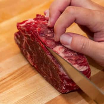 man using a knife to cut beef