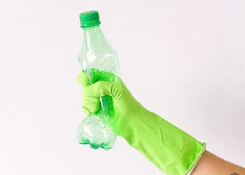 person wearing green gloves while holding a plastic bottle